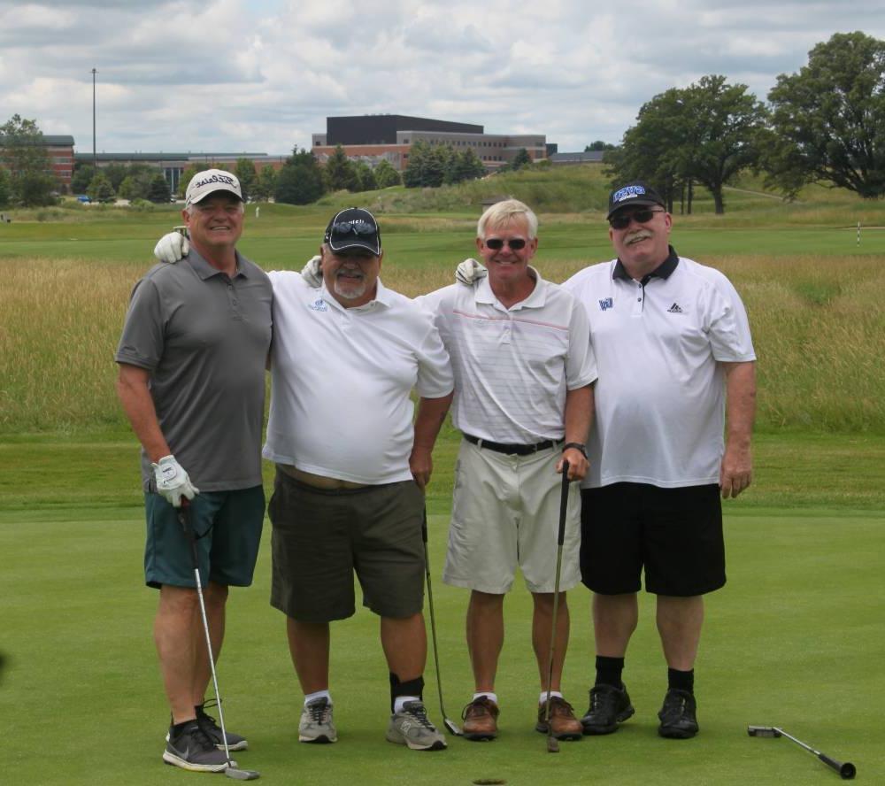 4 men pose for pic on course